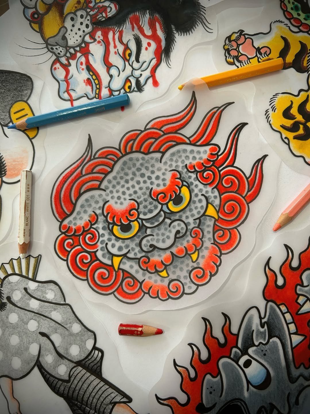 Desenho a cores de uma cara de leão estilizada, rodeada de lápis e marcadores